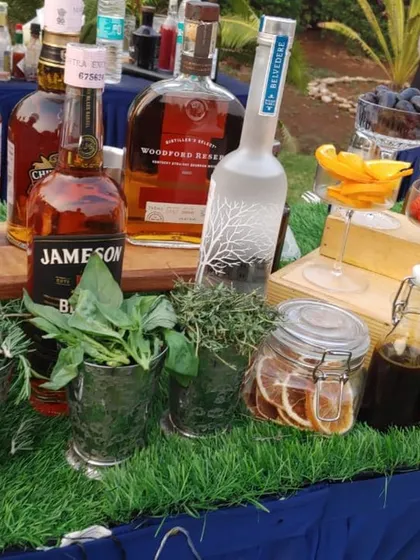 A selection of premium spirits alongside fresh herbs like rosemary and basil. This showcases the quality ingredients I use, combining top-shelf liquor with garden-fresh elements for superior cocktails.