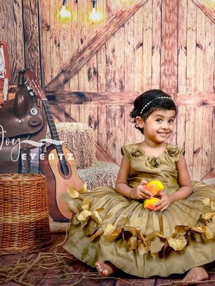 A rustic warehouse or barn theme for a unique kids' photoshoot. The set includes hay bales, a guitar, and a saddle against a wooden wall, perfect for a country-style portrait.