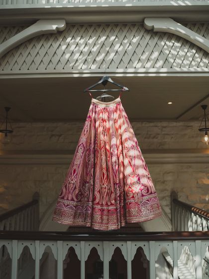 A beautiful shot of the bride's lehenga hanging against the classic architecture of the Taj Mahal Palace, a detail shot that sets the tone for a day of elegance.