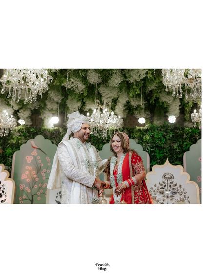 A wide shot of the couple on their beautifully decorated stage, surrounded by chandeliers and floral arrangements.