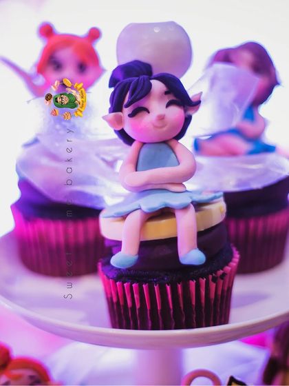 A close-up of a fairy cupcake from the enchanted dessert table. This little fairy is sitting peacefully on top of the chocolate cupcake, ready to add a touch of magic to the party.