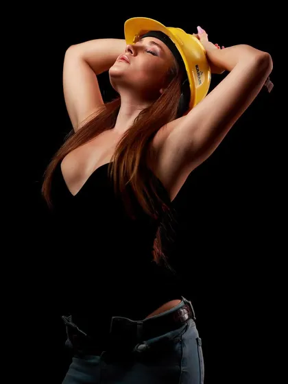 A conceptual portrait of a model in a yellow hard hat, creating a playful and unexpected theme within a studio setting.