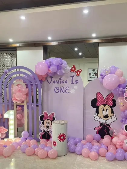 For Vamika's first birthday, we created this beautiful Minnie Mouse wonderland. The setup includes a custom arched backdrop, a full balloon garland in shades of purple and pink, and a light-up marquee number '1' to mark the special milestone.