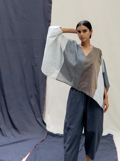 An artistic, asymmetrical top with panels of white, grey, and brown, paired with navy trousers for a modern, deconstructed look.