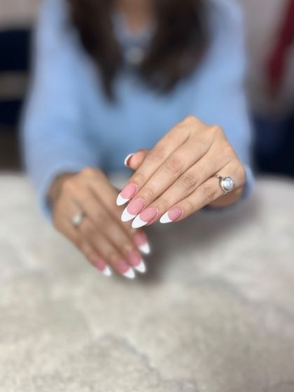 A classic almond-shaped French manicure. The clean lines and perfect shape are a testament to professional skill.