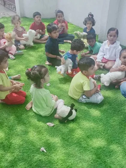 A quiet moment during our Summer Fun Fest. After a morning of activities, the children gathered with their favorite teddy bears for a story, enjoying the fresh air and the company of friends in our green outdoor space.