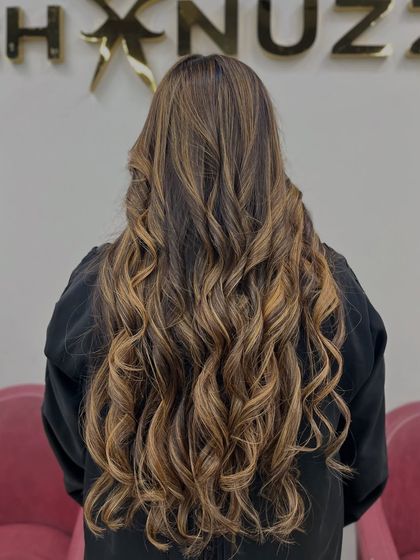 The full length of this light brown and blonde blend, styled in glamorous curls.