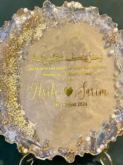 A beautiful resin engagement plaque designed to celebrate a new union. This piece features the couple's names, their special date, and a Quranic verse, all set in a shimmering gold and pearl design with a geode-style edge.