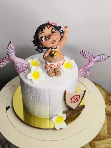 How far I'll go to make a cute cake! This design features a hand-sculpted baby Moana topper, complete with her necklace and flower. To make it extra special, I added some whimsical mermaid tails and tropical flowers for a fun island vibe.