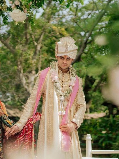 The couple holds hands as they take their first steps as husband and wife, framed by lush greenery.