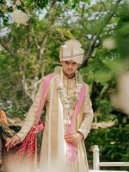 A couple stands together during their ceremony, framed by lush greenery and floral decor.