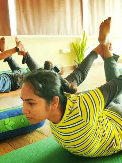 Students practicing Dhanurasana (Bow Pose) in class. This pose strengthens the back muscles, improves posture, and stimulates the abdominal organs.