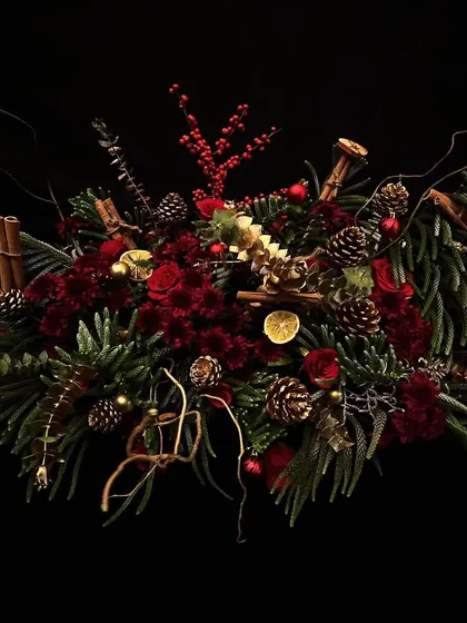 From extraordinary woody table centerpieces to the perfect eye-catching wreath, I bring the magic. This design is sweetly scented with cinnamon and pine, featuring deep red flowers and festive foliage.