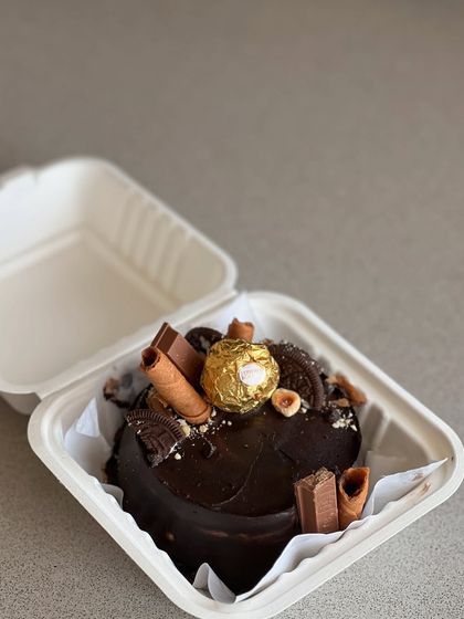 A close-up of a heart-shaped bento cake, overloaded with Ferrero Rocher, KitKat, and other chocolatey goodness.