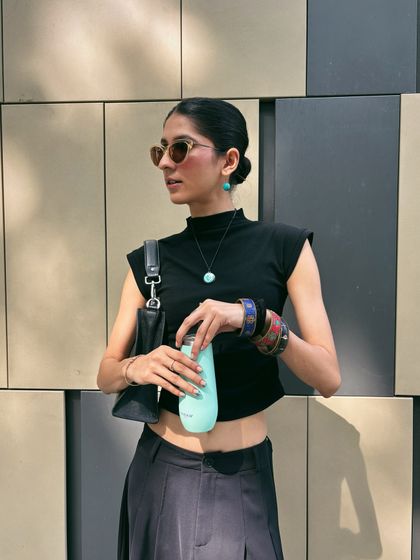 The same all-black outfit in focus. A cropped mock-neck top, wide-leg trousers, and pops of turquoise jewelry make for a chic and modern look.