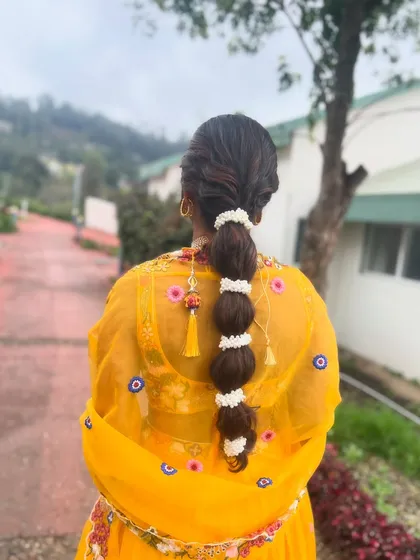 The bubble braid seen in an outdoor setting, showing how beautifully it complements the vibrant yellow of the client's outfit.