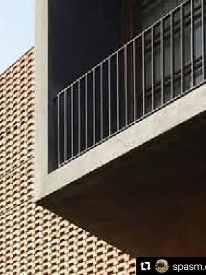 A close-up of the Ishtika house shows the interplay between the textured brick, the smooth concrete of the cantilevered box, and the soft foliage of the garden below.