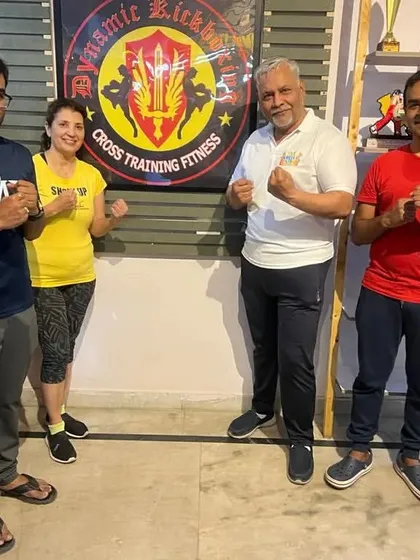 Posing by the Dynamic Kickboxing logo. We are proud of the community we have built.
