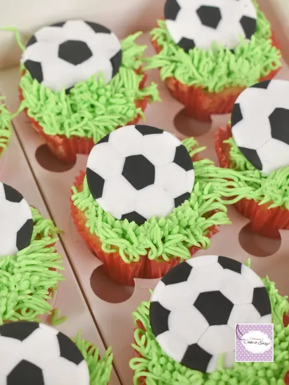 Football cupcakes with piped buttercream grass and fondant soccer balls.