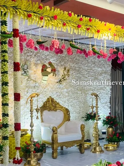 A side view of a traditional stage, highlighting the columns of jasmine garlands and the hanging floral parrots. This design is filled with classic South Indian wedding elements.