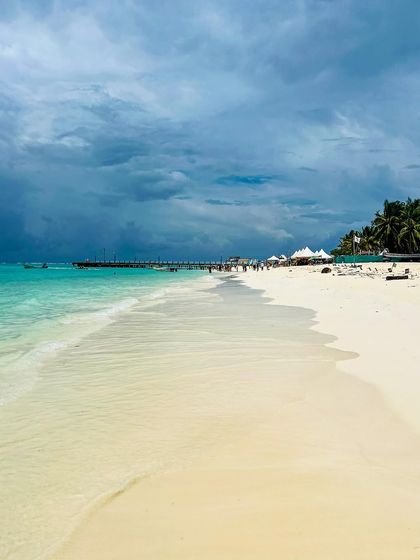 The pristine, untouched look of a white sand beach in Lakshadweep under a dramatic, cloudy sky. This image captures the raw, natural beauty of the islands.