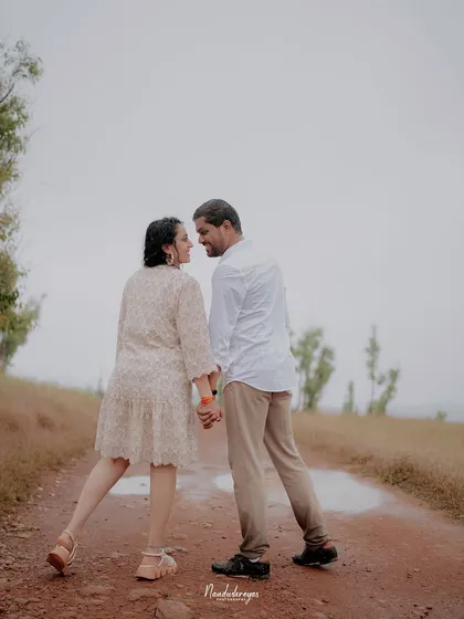 A couple looks back at the camera while walking down a dirt road, a simple yet engaging shot that invites the viewer into their journey.