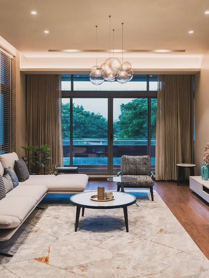 We designed this living room to be a space where style meets serenity. The composition balances a comfortable L-shaped sofa with a modern media unit and ambient lighting from a bubble chandelier, creating a warm and inviting atmosphere for timeless conversations.