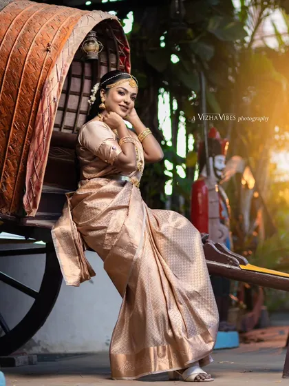 A full-length shot of a model in a traditional muhurtham saree, posing elegantly by a vintage-style cart.