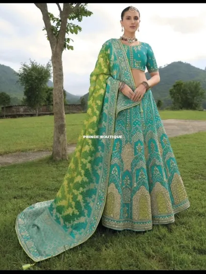 A full-length view of this unique lehenga, showing the combination of a teal embroidered skirt and a vibrant green and teal dupatta.