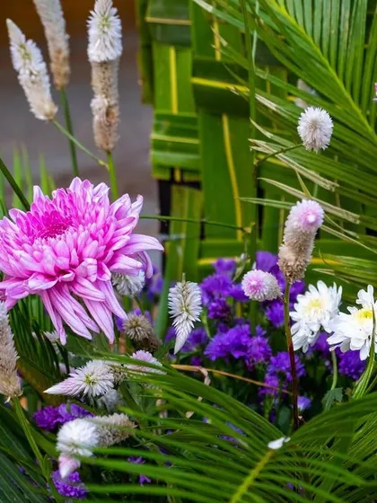 A close-up of the vibrant floral arrangements used throughout the traditional wedding decor, featuring pink chrysanthemums and purple statice.