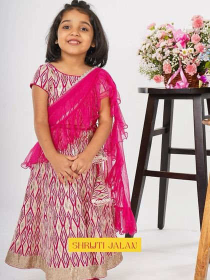 This little girl looks radiant in my pink and gold printed lehenga with a pre-draped fuchsia dupatta. It’s a vibrant and soulful style, perfect for celebrating Diwali or any festive occasion.