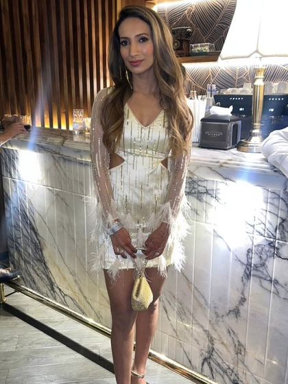 A full view of the custom ivory short dress, showing how the feather details on the hem and cuffs tie the whole look together. It's a fun, flirty, and sophisticated choice for a cocktail event.