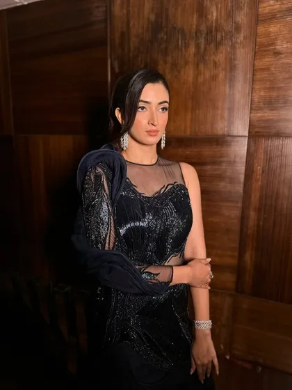 This shot captures the moodiness and glamour of the look. The dark, dramatic outfit is complemented by a makeup look that is equally powerful.