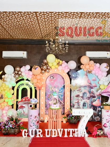 An elaborate enchanted forest and butterfly themed 7th birthday. This large-scale decoration includes mushroom props, fairy cutouts, and multiple arches.