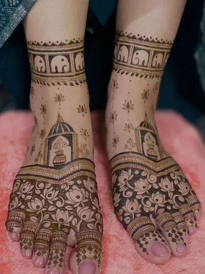 This foot mehendi is filled with traditional elements. It features a kalash, lotus flowers, and a band of elephants, creating a beautiful and auspicious design.