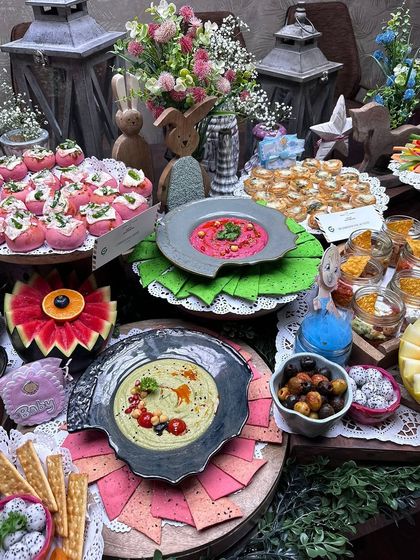 A close-up of our baby shower grazing table, showing the intricate details. Notice the flower-carved watermelon, colourful dips, and a variety of crackers and olives, all beautifully arranged.