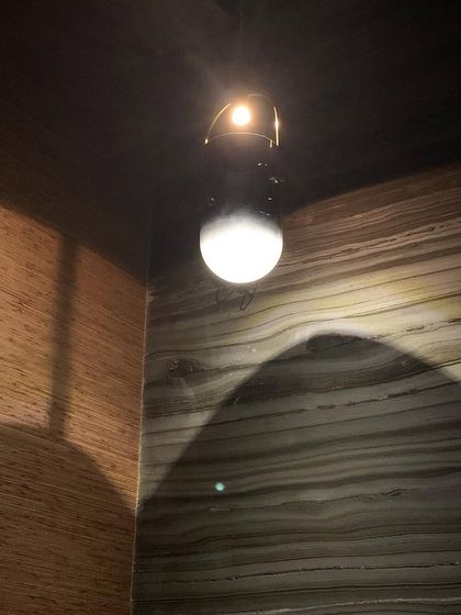 A single, elegant light fixture against a backdrop of wood and stone, showcasing the beauty of minimalist lighting.