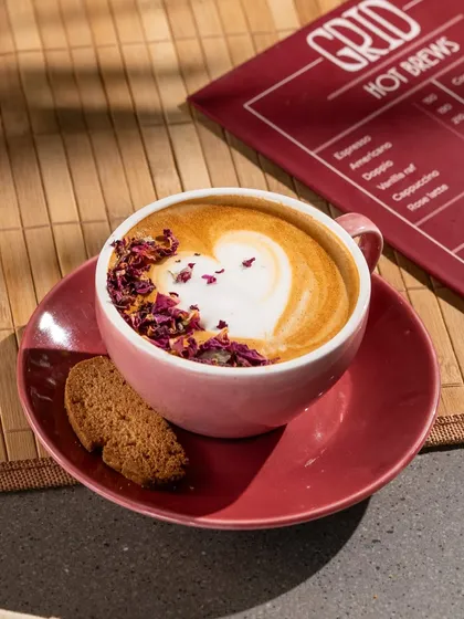 A wider shot of the rose latte, showing more of the menu and the cafe's branding.