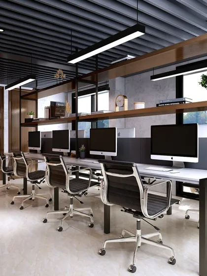 The open workstation area is designed with long desks and overhead shelving, maximizing space and promoting collaboration. The industrial-style ceiling and lighting add a modern touch.