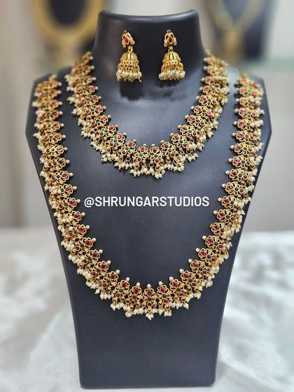 This gorgeous two-piece set features a necklace and a matching long haar, both adorned with red and green stones and delicate pearls. It's a versatile choice for any bride.