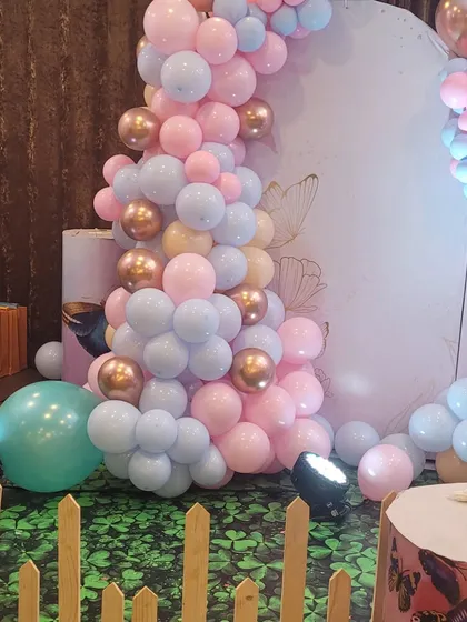 A detail shot of the balloon decor and flooring for the butterfly party. The green grass-like floor covering and wooden fence add a garden feel to the setup.