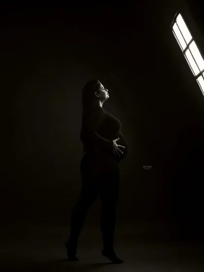 An artistic shot showing the studio setup. The client is silhouetted against the bright studio light, creating a powerful and modern black and white image that feels both raw and beautiful.