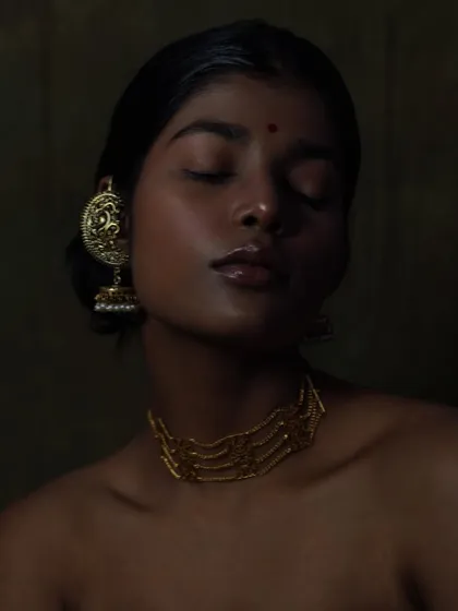 This serene portrait is all about the interplay of light and shadow. The golden tones of the jewellery and the glossy lips create a rich, luxurious feel.