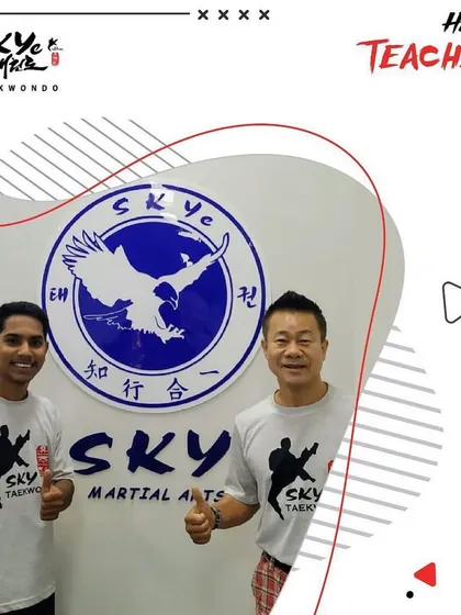A student blossoms under the care of a teacher. Our instructors stand proudly in front of the SKYe Martial Arts logo, representing our commitment to mentorship.