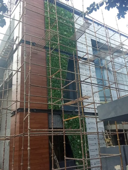 The same building during installation, showing the green panels being fitted alongside new wooden facade panels.