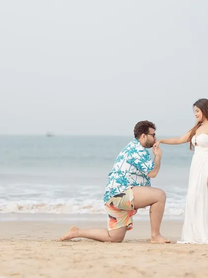A classic proposal shot on the beach in Goa, with the groom on one knee against the backdrop of the ocean.