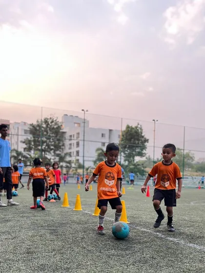 Two young players focus on their ball as they participate in a dribbling exercise.