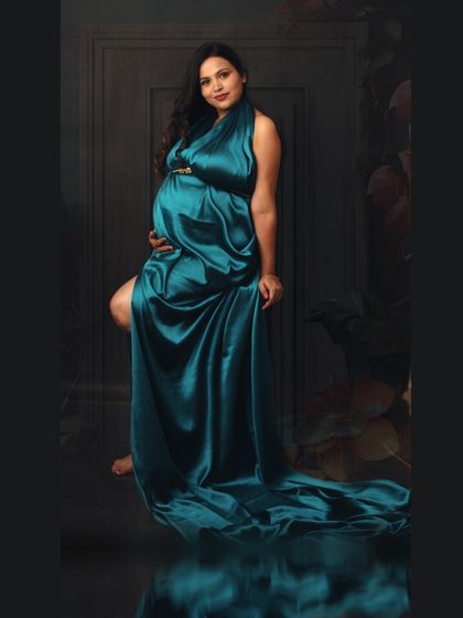 Ruling the kingdom of maternity. A powerful pose in a teal satin gown, with the fabric draped elegantly to create a regal and confident portrait.