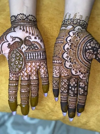 An asymmetrical design for a modern look. One hand features two peacocks, while the other has a large, detailed mandala pattern.