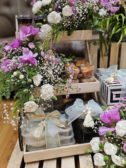 Another angle of the 70th birthday hamper, showing the artful arrangement of food containers, gift boxes, and fresh flowers. It's a feast for the eyes as well as the palate.
